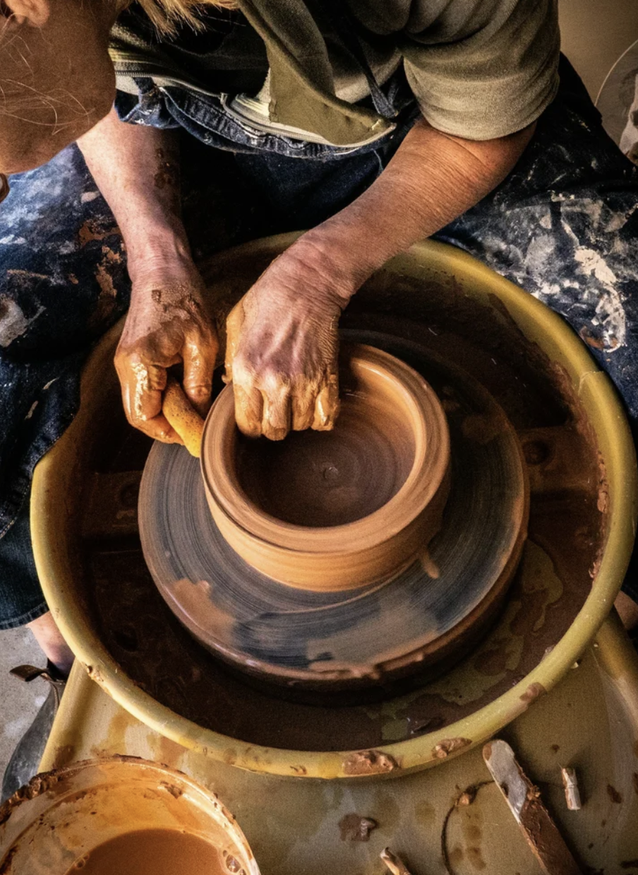 A potter shaping a vessel on the wheel